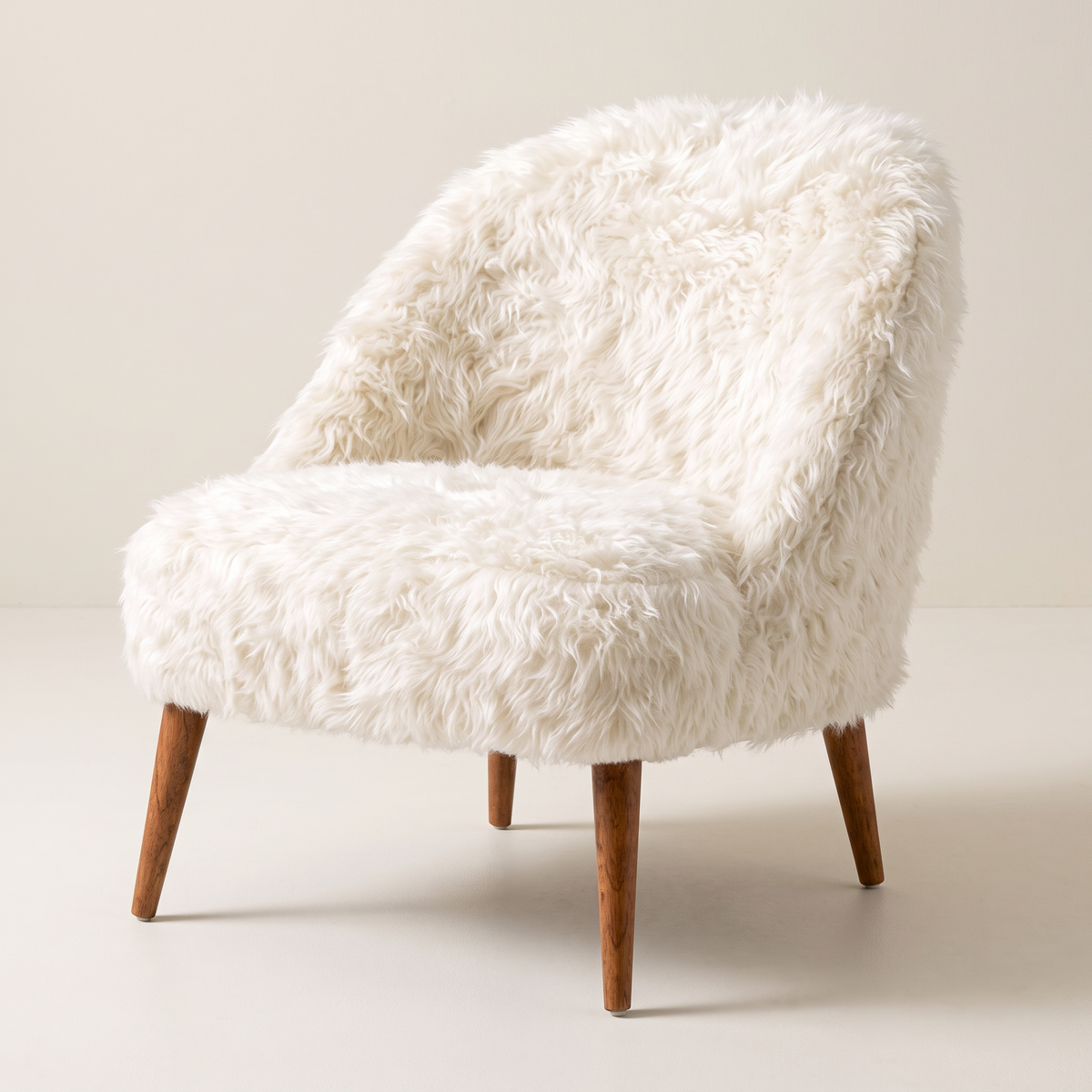 Soft Cloud slipper lounge chair in ivory shaggy faux fur with tapered wooden legs, front three-quarter view