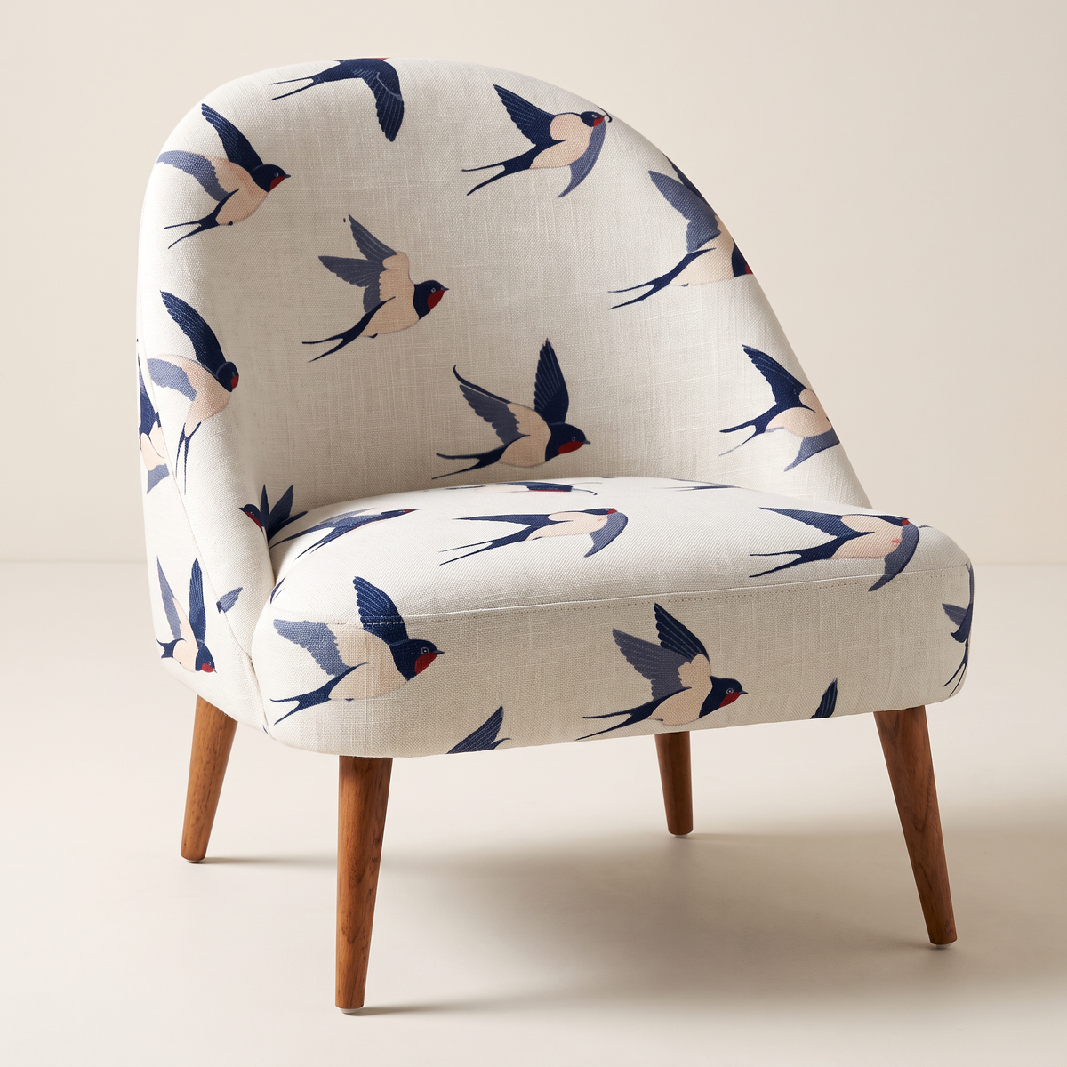 Soft Flight slipper lounge chair in off-white swallow-print fabric with tapered wooden legs, front three-quarter view