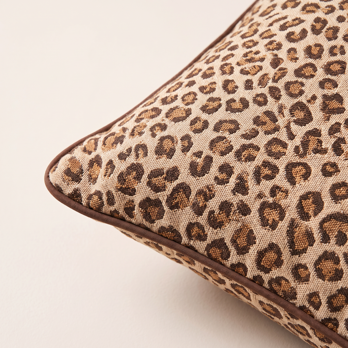 Close-up of Spot Jacquard Cushion corner showing woven leopard rosettes and piping