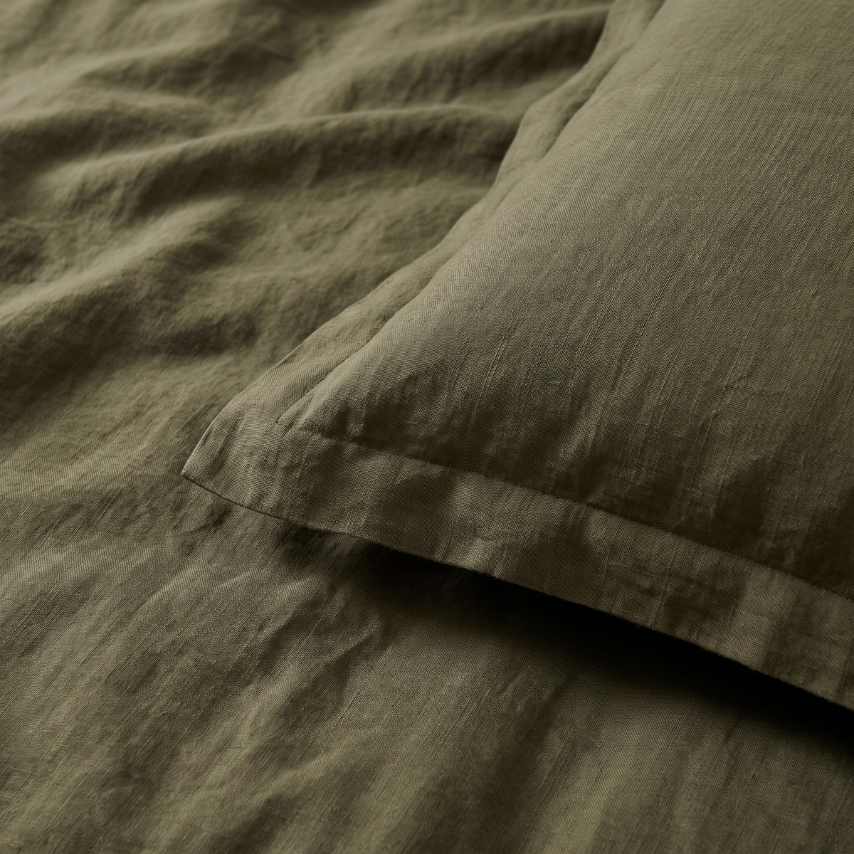 Close-up of Stonewash Olive sham flange edge and softly wrinkled olive linen-cotton texture
