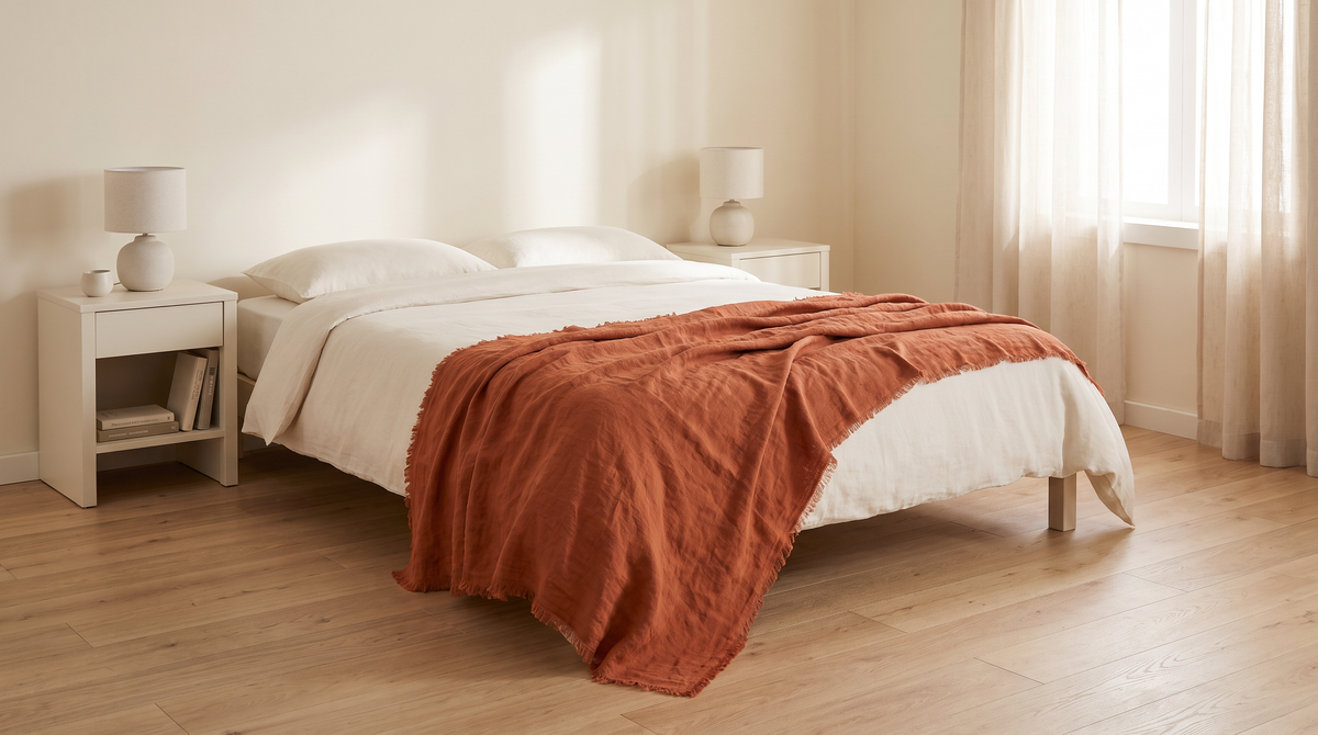 Stonewashed Linen Throw in rust draped over the end of a bed in a calm bedroom