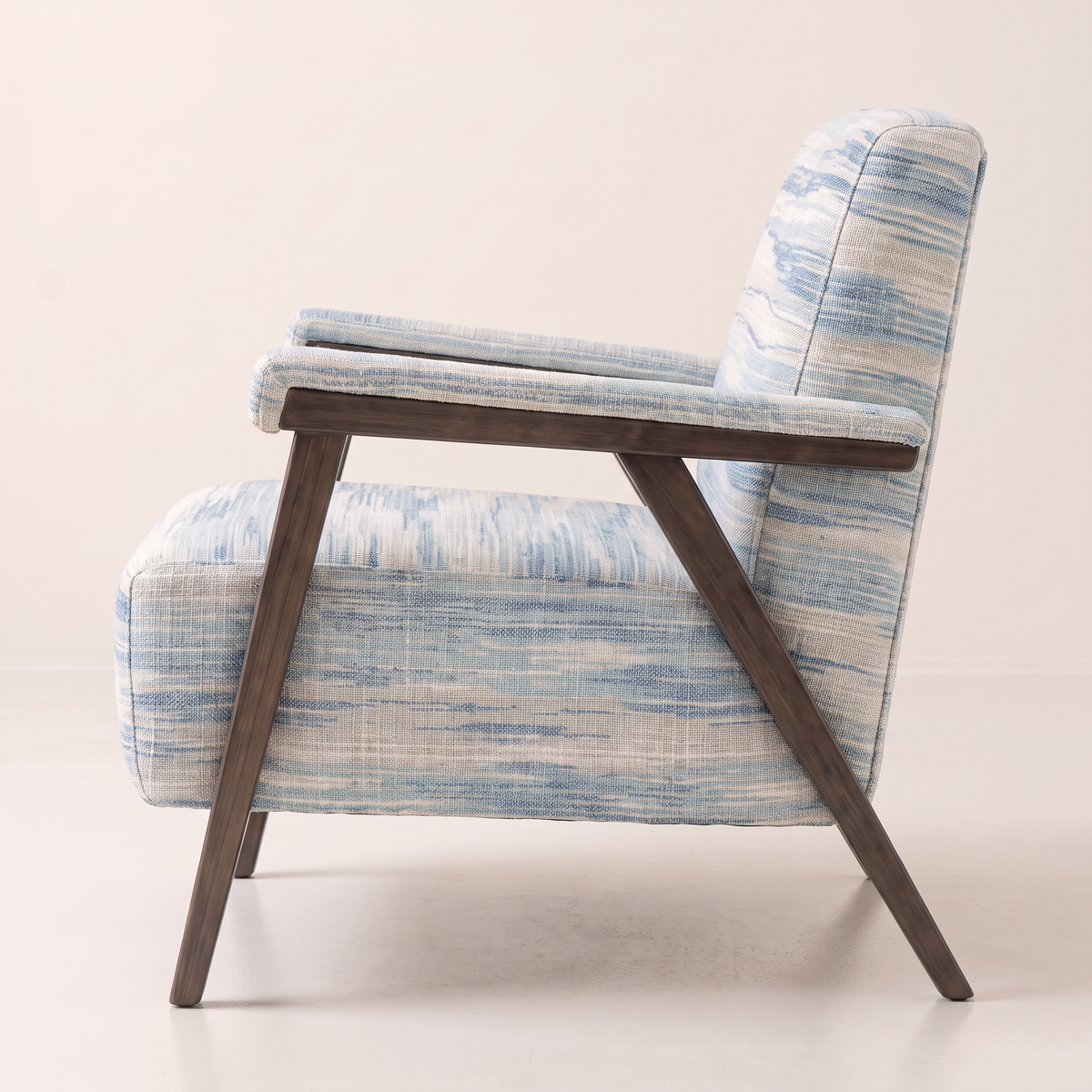 Strata Blue lounge chair showing its splayed dark wooden legs and padded arm, side profile view