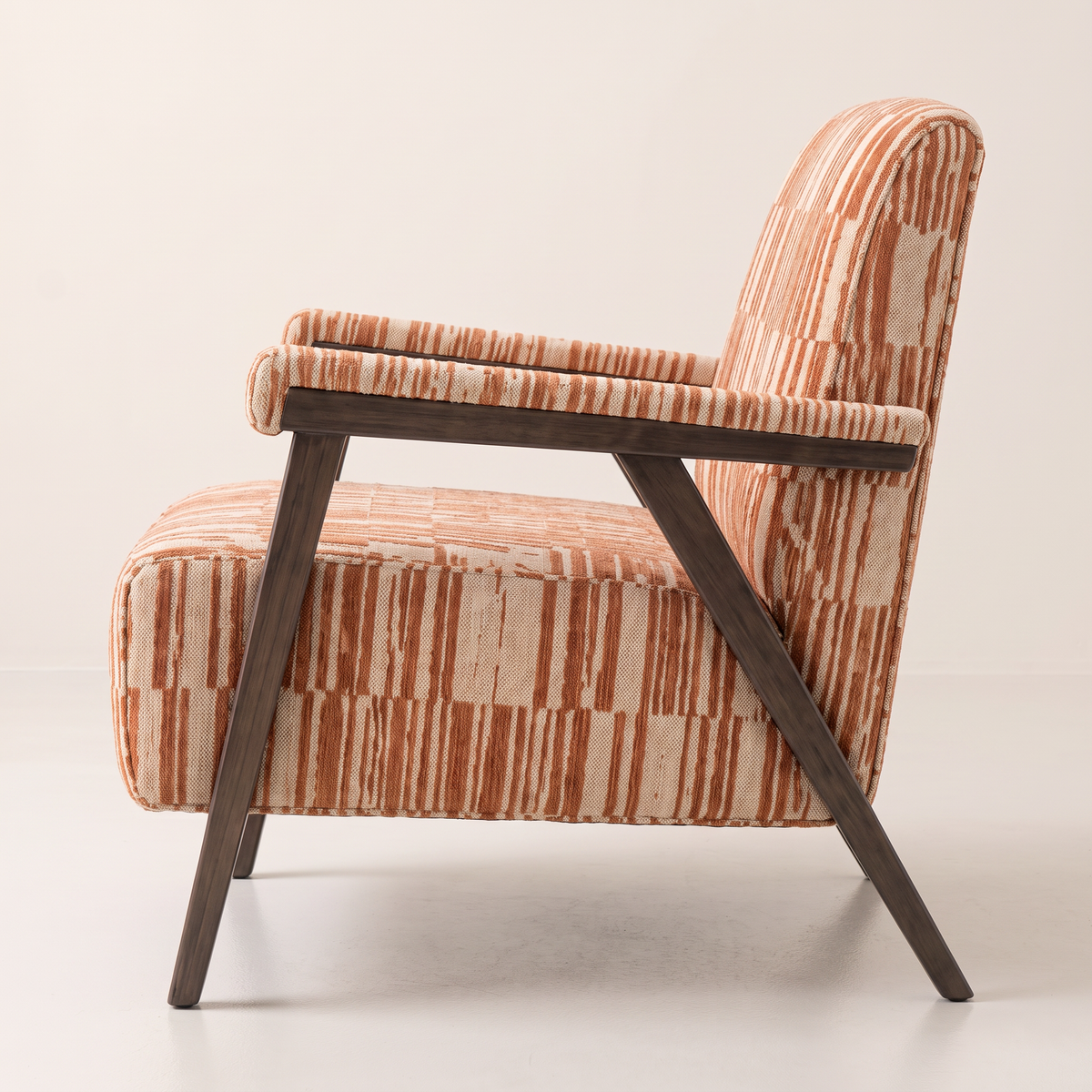 Strata Red lounge chair showing its splayed dark wooden legs and padded arm, side profile view