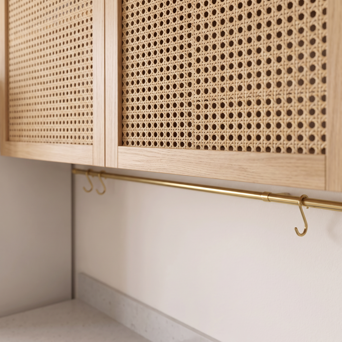 Studio Line detail of woven cane wall-cabinet doors in light oak frames above a brass hanging rail