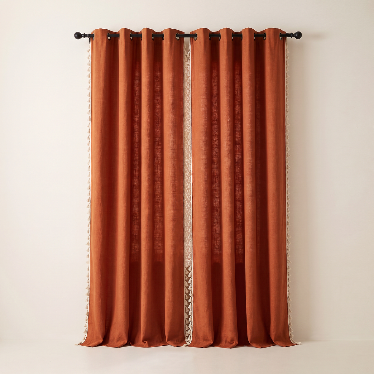 Tassel Slub Eyelet rust cotton slub curtains fully drawn, tassel trim on both side edges of each panel, straight front view
