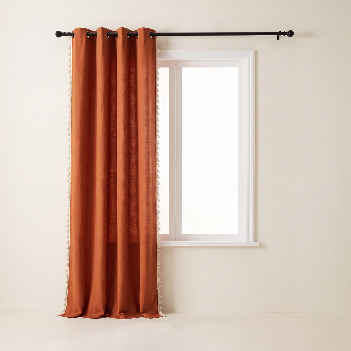 Tassel Slub Eyelet rust curtain panel stacked to one side of the window, tassel trim on both side edges