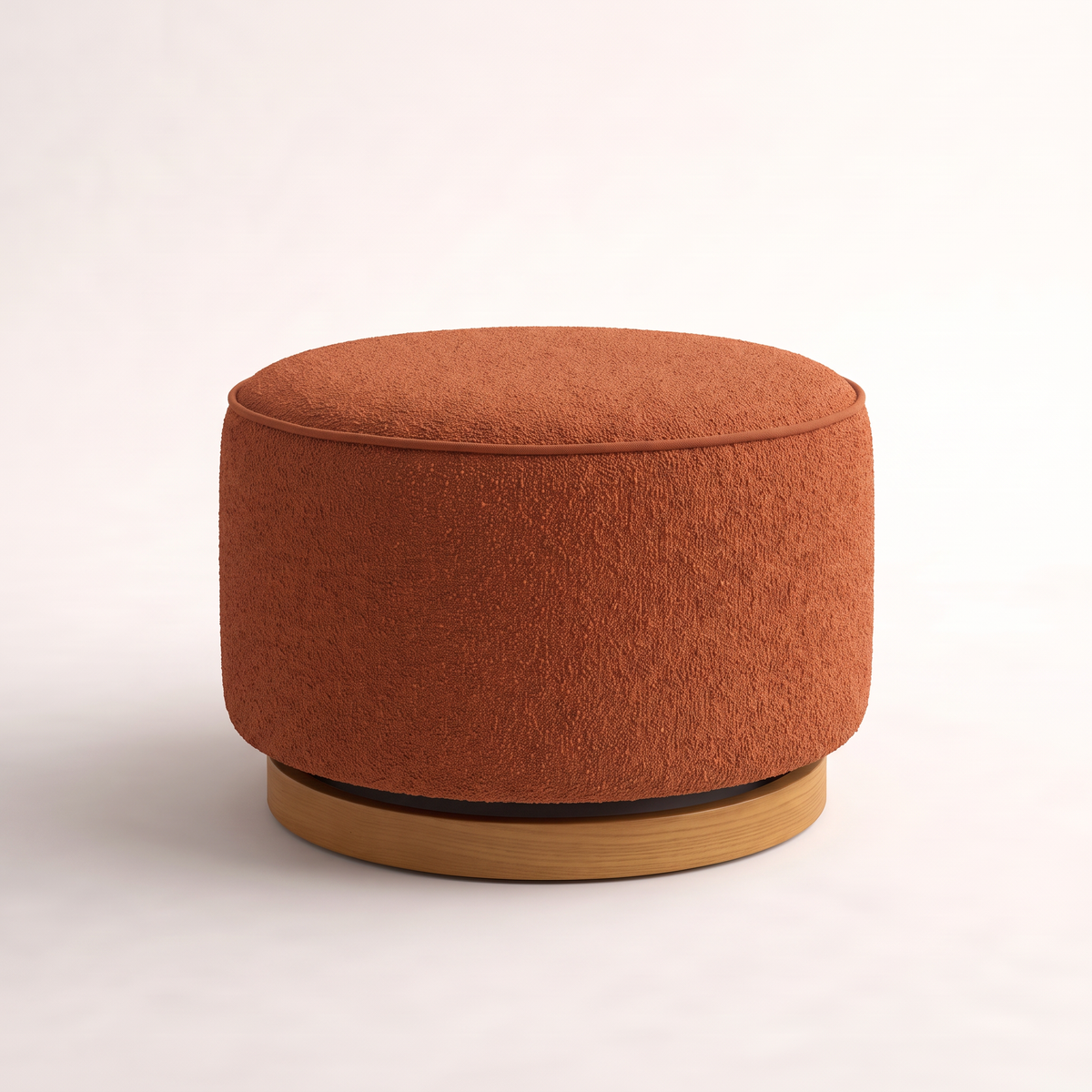 Tondo Rust round drum ottoman in rust bouclé with welt piping on a recessed honey ash plinth, front three-quarter view