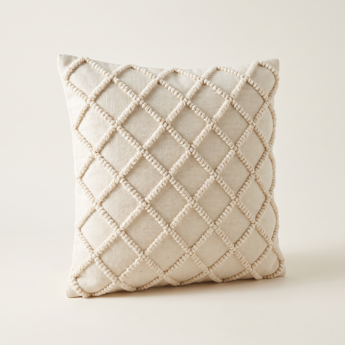 Tufted Loop Cushion in ivory cotton with raised wool loops in a diamond lattice, front three-quarter view