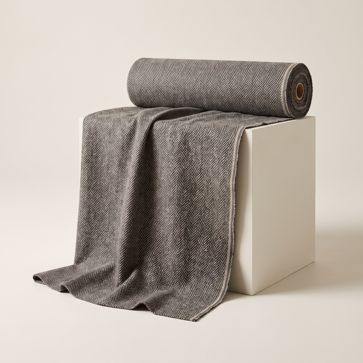 Tweed Herringbone upholstery fabric, charcoal and oat herringbone tweed, unrolled from a bolt and draped over a studio plinth