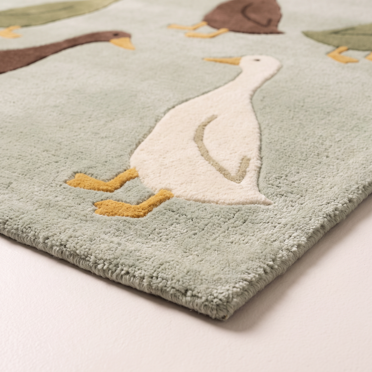 Waddle Kids Rug corner close-up showing tufted wool pile, a cream duck and bound edge