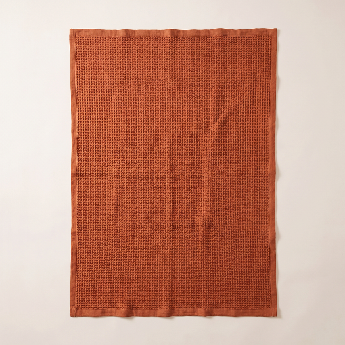 Waffle Cotton Throw in rust spread flat, overhead view of the whole throw with hemmed edges