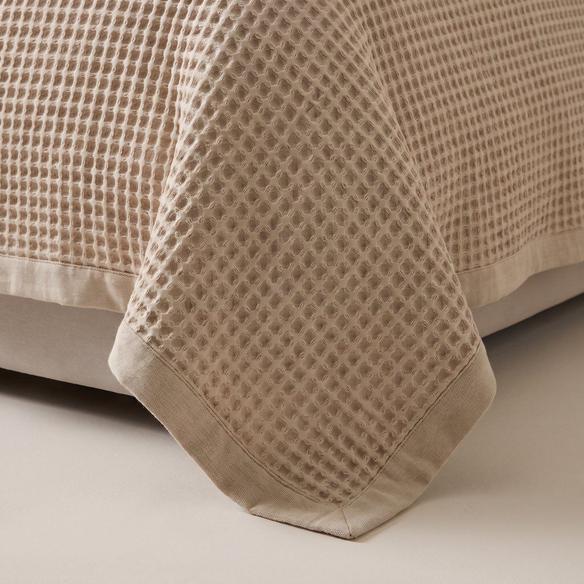 Close-up of Waffle Weave Bedcover square waffle cells and hemmed edge in oat cotton